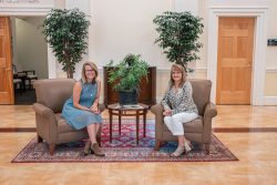 Two women, Dr. Alisa Leckie and Dr. Taylor Norman, sitting in chairs in the middle of a clean room with plants behind them